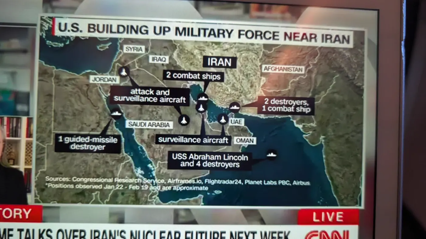 Live CNN on seatback screen: US Building Up Military Force Near Iran showing carrier strike groups, destroyers, and surveillance aircraft right under our flight path